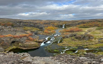 Scenic view of Gjain valley with waterfalls, lava formations, and autumn colors in the Icelandic Highlands.