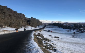 Walking path between cliffs in snowy Thingvellir National Park.