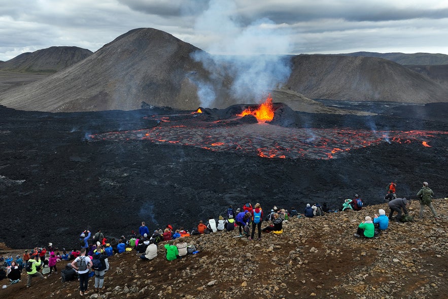 I visitatori ammirano la lava che erutta dalla fessura vulcanica nella valle di Meradalir.