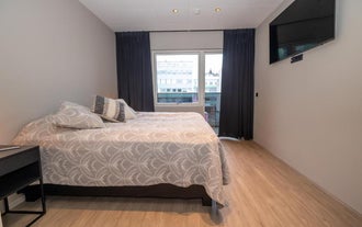 S10 Stylish Apartment in Akureyriのダブルベッドとテレビ付きのコンテンポラリーベッドルーム