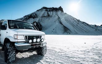 Een superjeep geparkeerd in een ijzig en bergachtig deel van de Mýrdalsjökull-gletsjer tijdens een Katla-ijsgrottentocht.