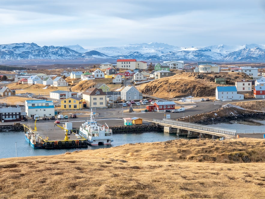 Stykkisholmur's cityscape from the harbor showing the Icelandic Eider Center and its surroundings with the snow-topped mountain ranges in West Iceland.