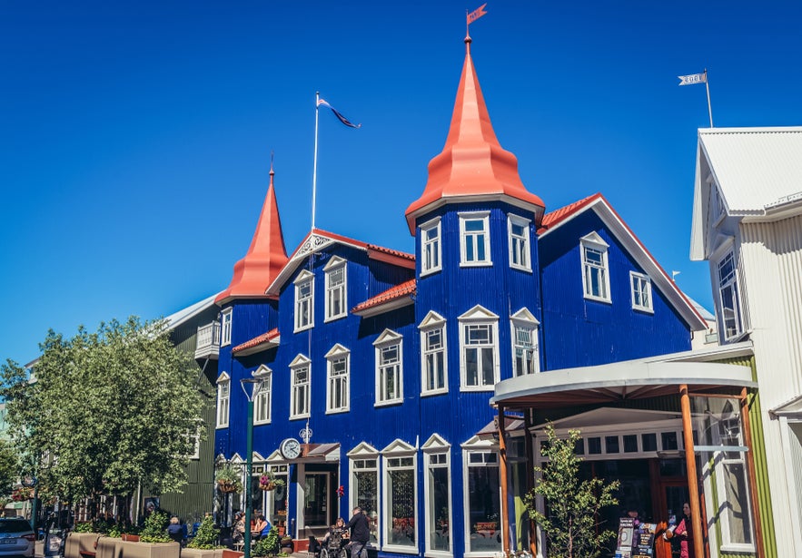 Unique blue building with red turret roofs of Blaa Kannan on a bustling street in Akureyri, Iceland.