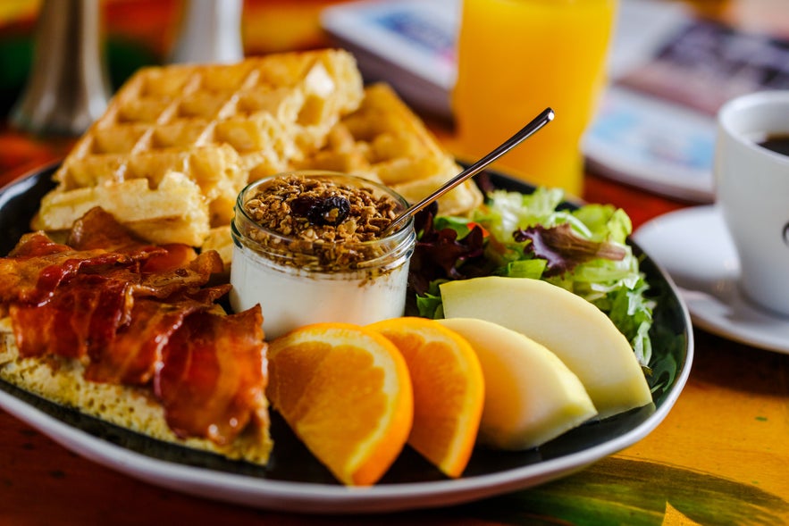 Hearty breakfast plate with waffles and bacon at Blaa Kannan Cafe in Akureyri.