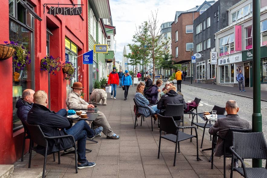 Mensen genieten van koffie aan buitentafels van een café aan de Laugavegur in Reykjavik overdag.