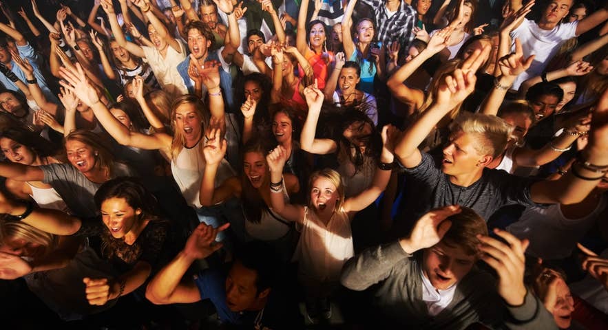 A crowd of Icelanders with arms raised, showing a range of hair colors and features.