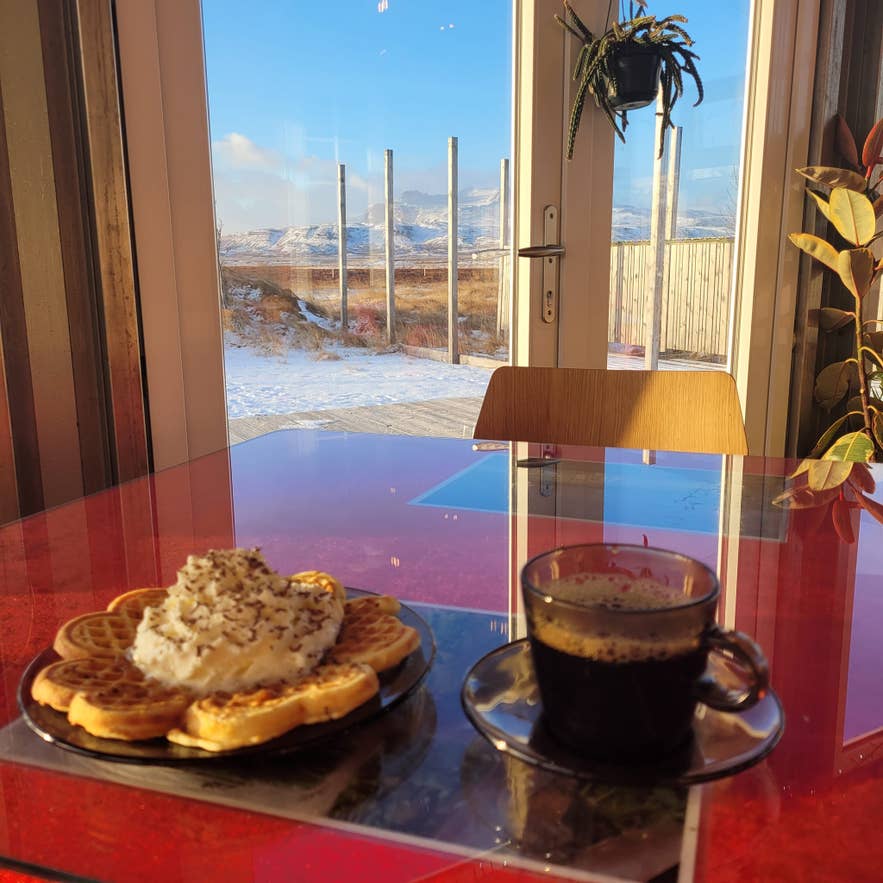 Gaufres au café et à la crème fouettée chez Hjá Góðu Fólki, avec des montagnes enneigées en arrière-plan.