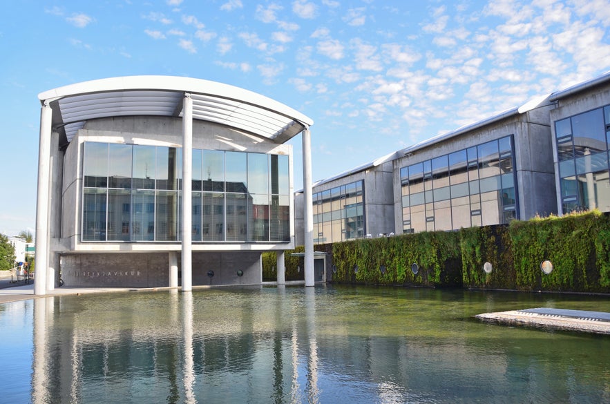 Facade of Reykjavik City Hall reflecting on the waters of Tjornin Pond.