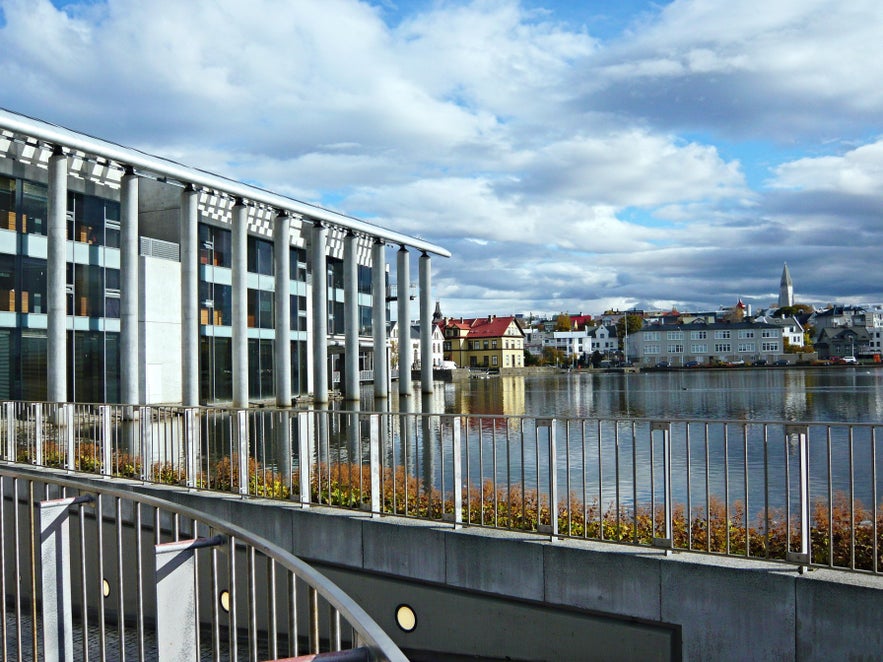 Reykjavik City Hall on the edge of Tjornin Pond with downtown Reykjavik skyline and waterfront reflections on a clear day