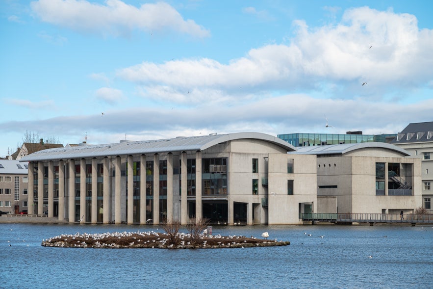 Reykjavik City Hall viewed across Tjornin Pond, showing its curved roof and modern concrete design in downtown Reykjavik