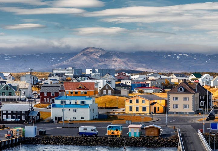 Coastal buildings in Stykkisholmur with cloudy skies and rugged terrain.