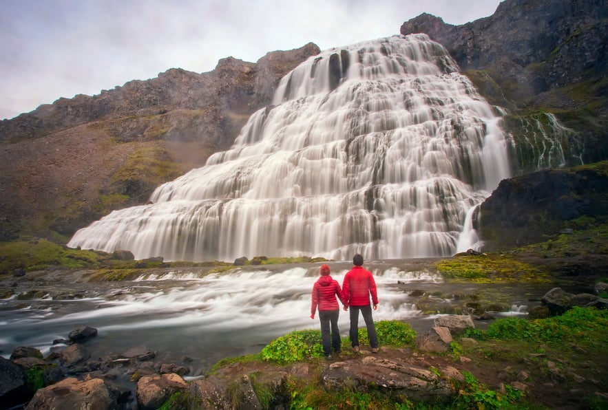 Couple standing in front of Dynjandi Waterfall in the Westfjords of Iceland.