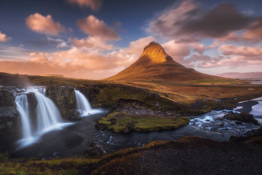 Iconic Kirkjufell peak with twin waterfalls flowing beneath in Iceland.