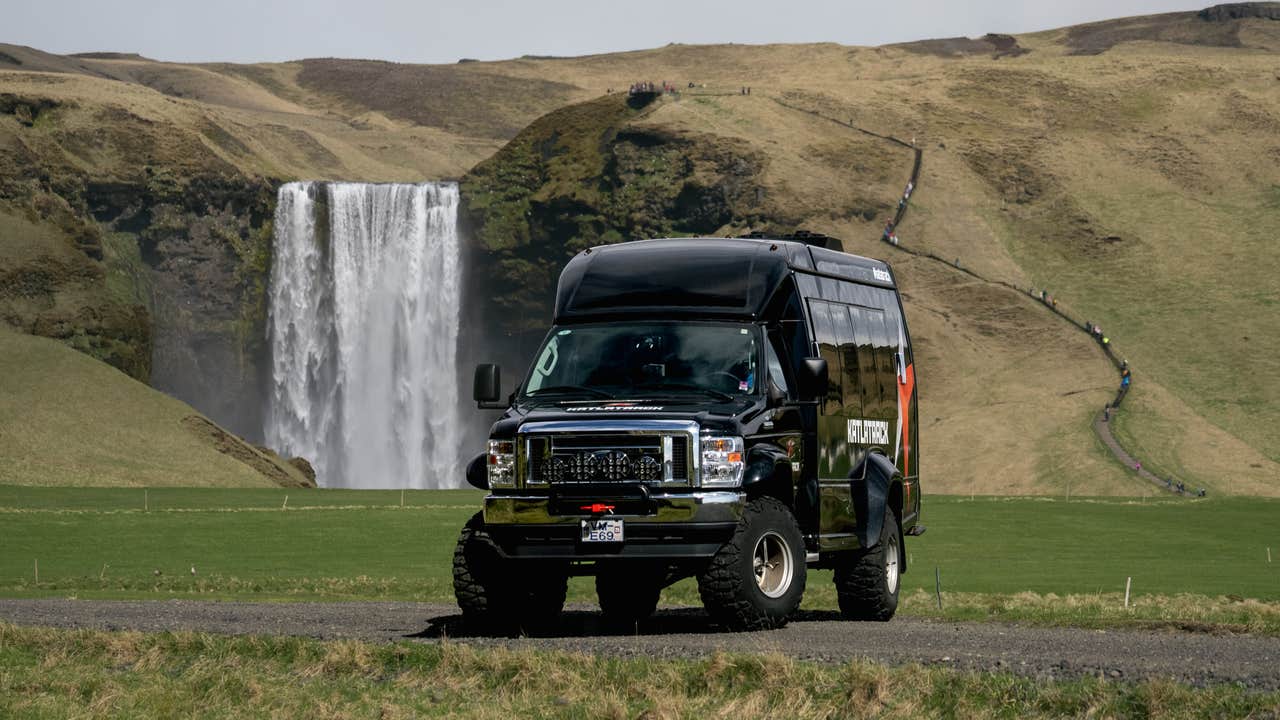 Tour super jeep parked near Skogafoss waterfall in Iceland, used for guided glacier and ice cave adventures.