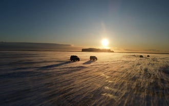 Dos Super Jeeps se dirigen hacia la cueva de hielo Katla desde Vík, en el sur de Islandia, bajo el resplandor del sol de la tarde.