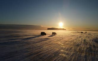 Twee Super Jeeps rijden richting de Katla-ijsgrot vanuit Vík in Zuid-IJsland, onder het warme licht van de middagzon.