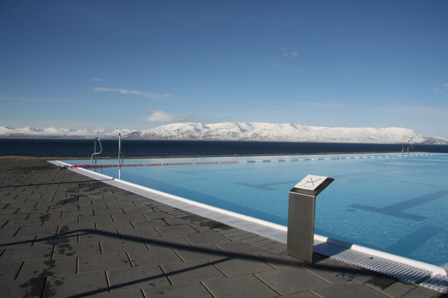 Hofsos swimming pool in North Iceland with snow covered mountains in the distance