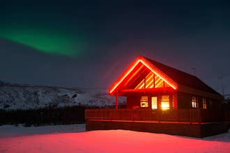 Gljufurbustadir Holiday Home illuminée la nuit avec les aurores boréales en arrière-plan.