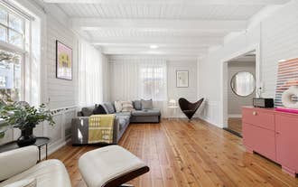 Spacious living room with a large gray sectional sofa, wood floors, and white paneled walls.