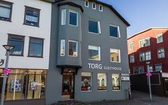 Front view of Torg Guest House in Akureyri with a gray facade and large windows facing the town square.