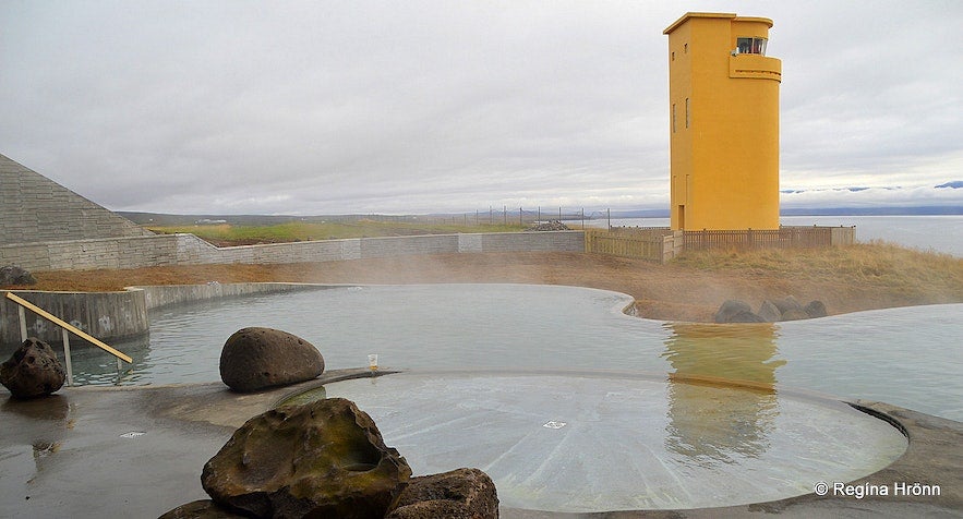 Bagni geotermali sul mare con vista su un faro.