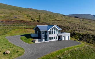 K17 Villa's two-story house with large windows, surrounded by grassy hills under a clear blue sky.