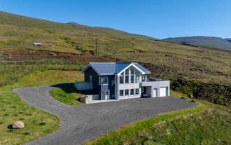 K17 Villa's two-story house with large windows, surrounded by grassy hills under a clear blue sky.