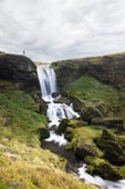 Man standing at the top of Selvallafoss waterfall, looking down.