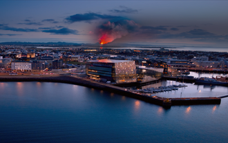 Een uitzicht op Harpa, waar de Volcano Express zich bevindt, met in de verte een vulkaanuitbarsting op Reykjanes.
