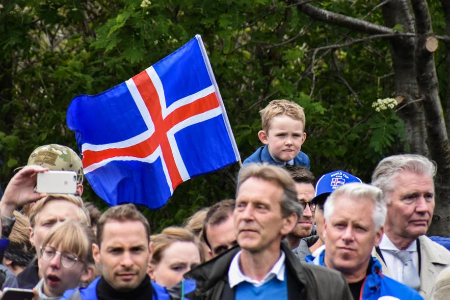 レイキャビクのオーストゥルヴォットル広場でアイスランド国旗を掲げて国民の日を祝う人々と家族。