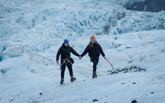 Two travelers exploring Falljokull Glacier on a guided glacier hike in South Iceland.
