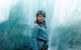 A climber smiles and poses for a photo in an icy canyon in Iceland.