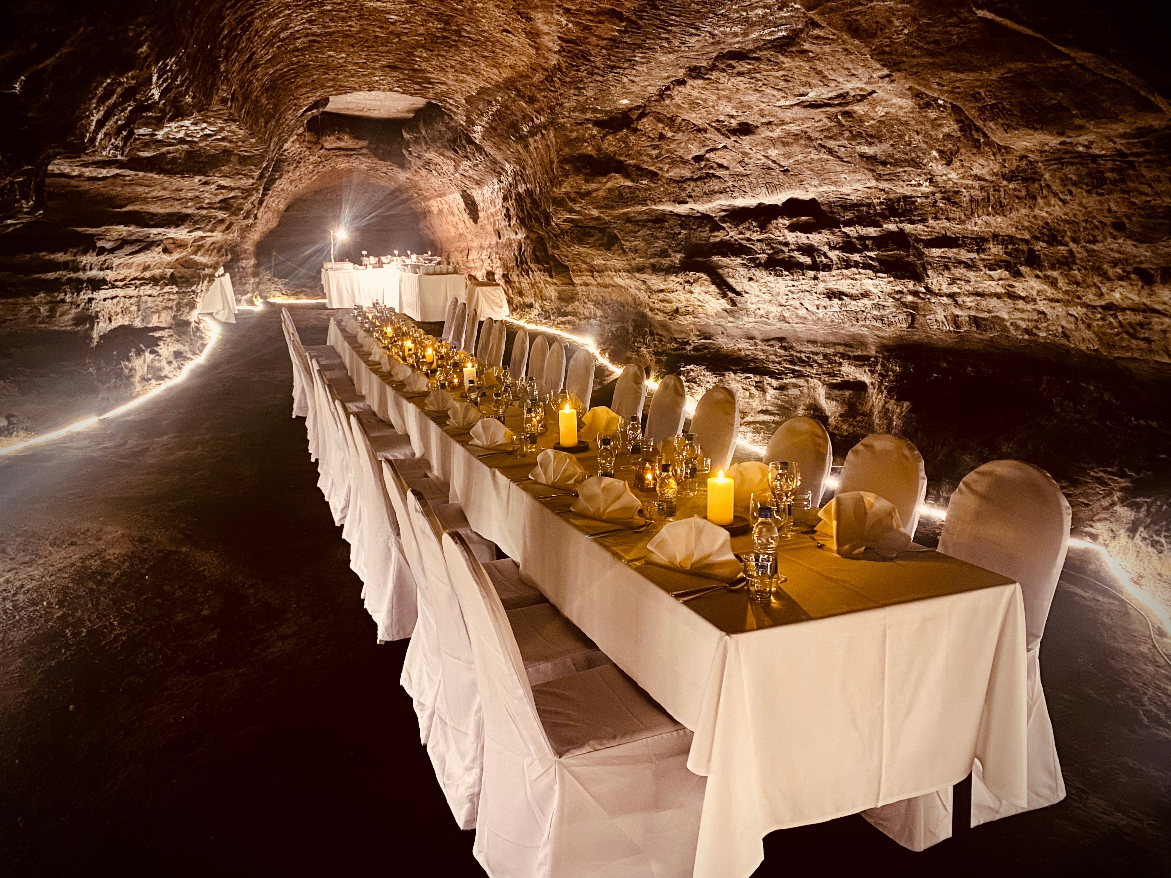Elegant candlelit three-course dinner set inside the natural lava walls of Raufarholshellir Lava Tunnel in Iceland.