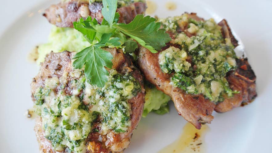 Grilled lamb chops topped with herb and garlic sauce, served over mashed potatoes.
