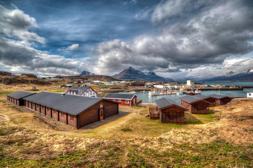 Scenic view of Djúpivogur village with colorful harbor, wooden cottages, and Búlandstindur Mountain in East Iceland.