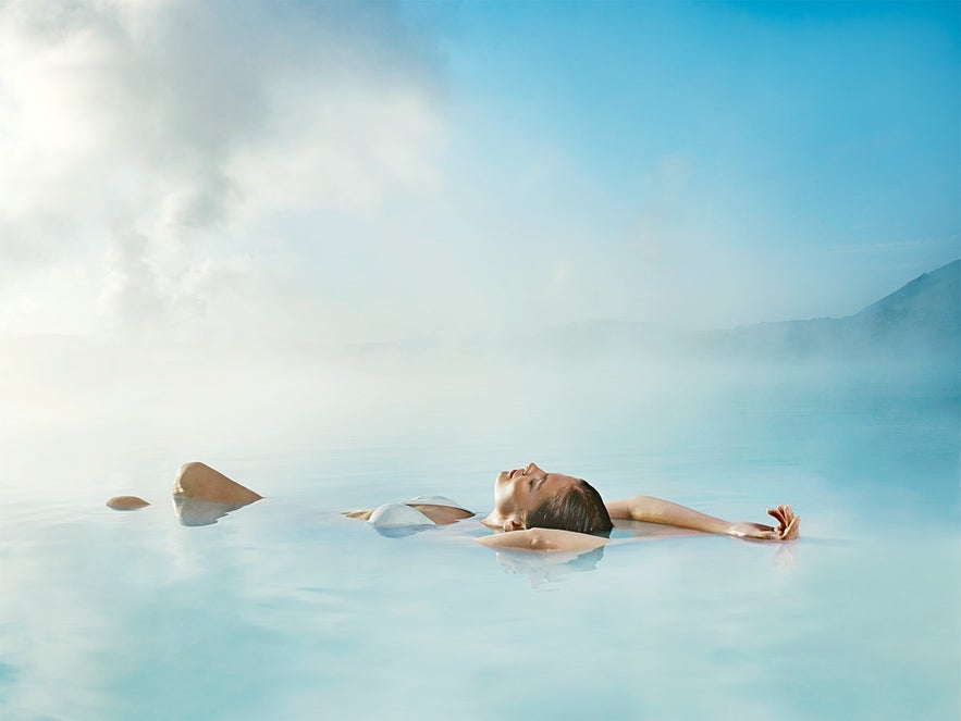 Een vrouw ontspant zich in het water van de Blue Lagoon