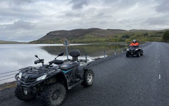 Reisende fahren ein ATV entlang eines Sees im Südwesten Islands.