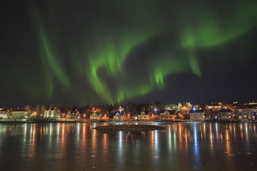 Northern Lights over city pond in Reykjavik, Iceland