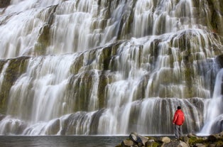 A tourist standing at the bottom of Dynjandi Waterfall in Westfjords, Iceland.