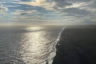 The sun shines on the waters of a black-sand beach on Iceland's South Coast.