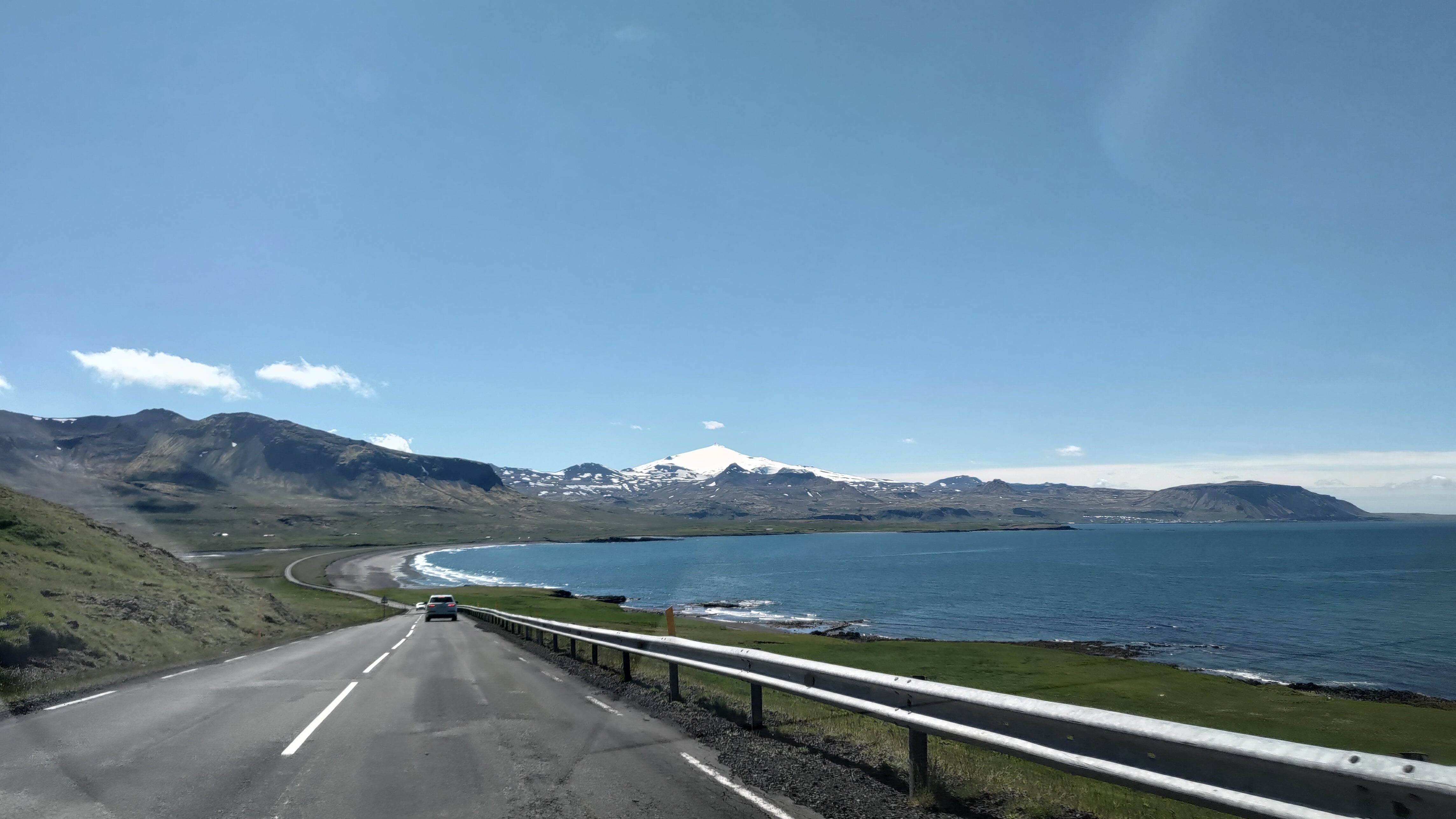 A long stretch of road leading to the snow-capped landscapes of Snaefellsnes Peninsula.