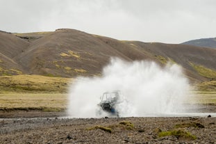 Water klatert als een ATV een beek oversteekt.