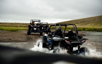 Tre persone che guidano un buggy ATV attraversano un torrente.