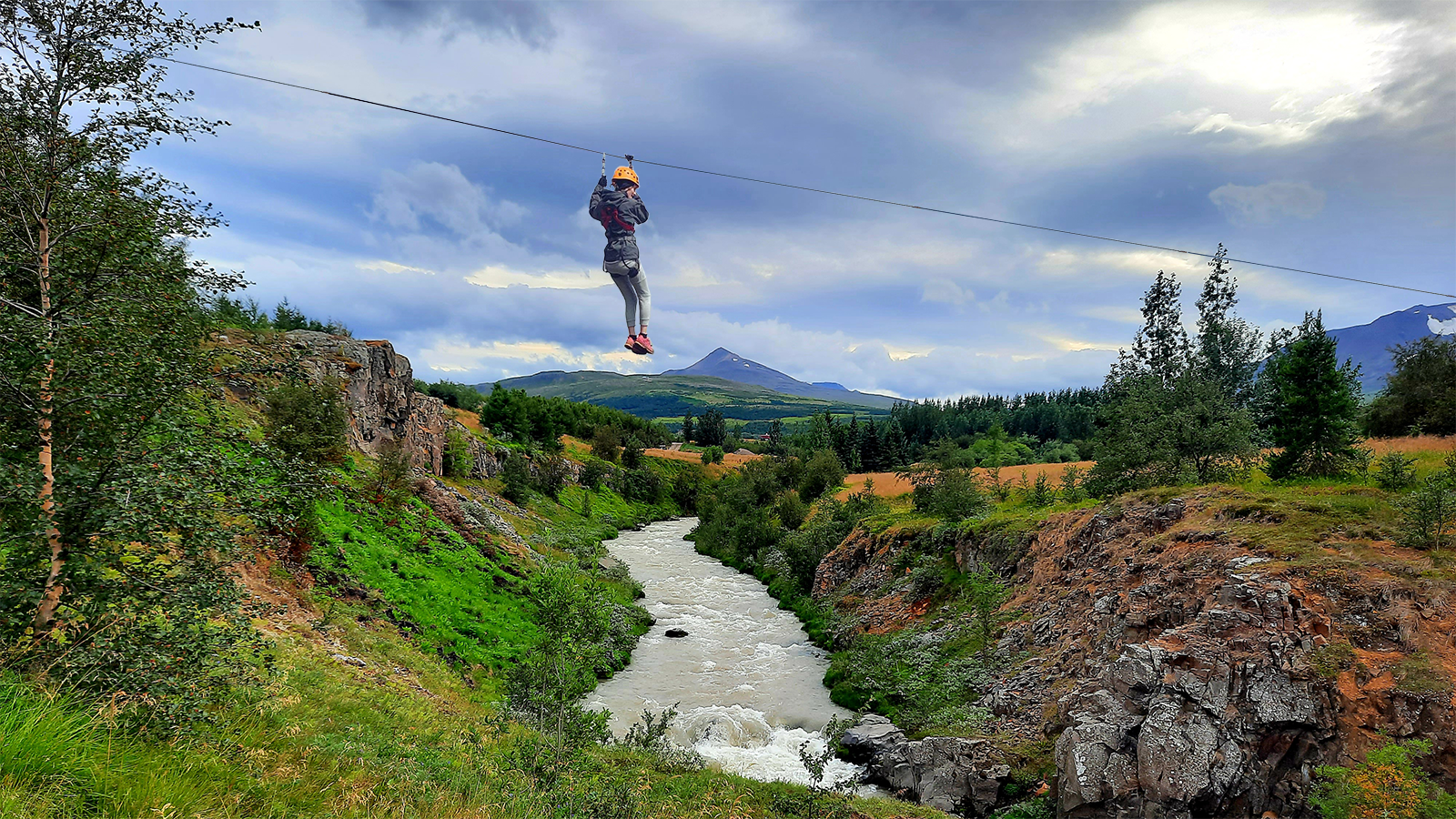 En person svæver over floden på Akureyri-zipline-turen.