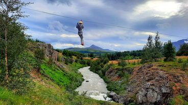 A person zip lines over the river on the Akureyri zipline tour.