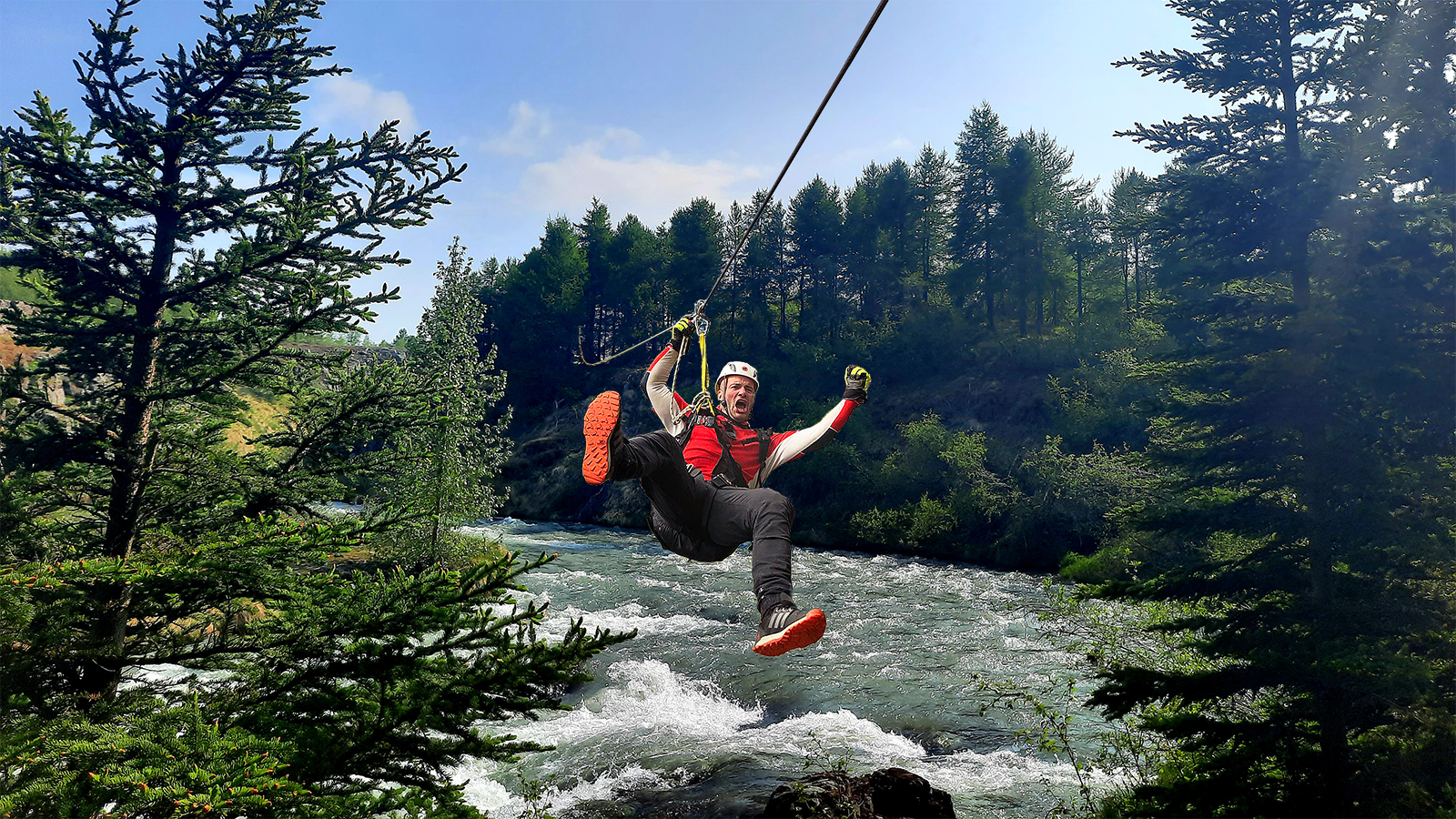 Un uomo si muove in zipline su un fiume durante il tour in zipline di Akureyri
