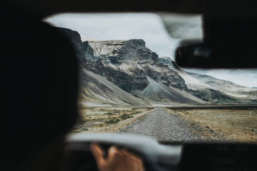 View from inside a car of snowy mountains on a remote Iceland road