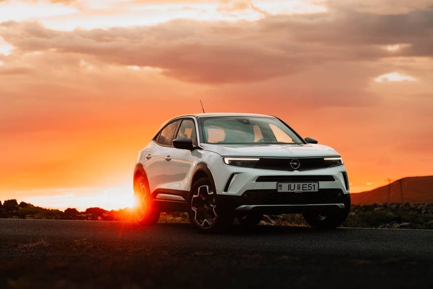 White electric SUV on an open road at sunset in Iceland