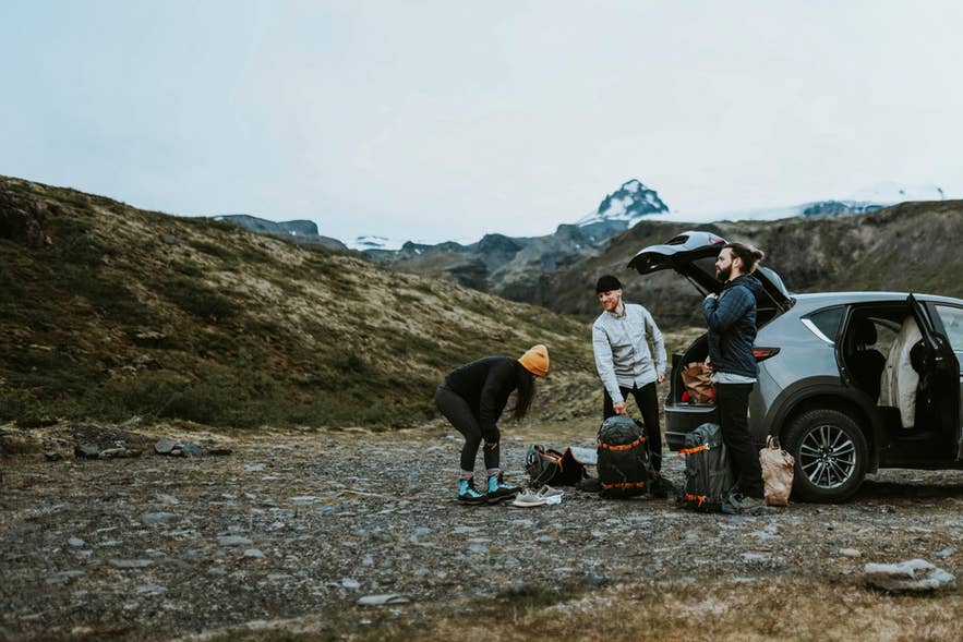 Travelers unpacking gear from an SUV in a rocky Icelandic valley