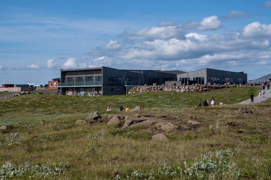 Bezoekerscentrum Gullfoss in de Gouden Cirkel van IJsland, met moderne houten architectuur, grasrijke omgeving en toeristen op een zonnige dag.
